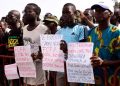 People hold signs during an anti-colonial demonstration against the regional CFA franc on the Place de l'Obelisque in Dakar on September 16, 2017. 
The CFA franc, which is pegged to the euro, is used in eight West African countries in the region, six of which are former French colonies. / AFP PHOTO / SEYLLOU